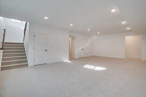 Below grade area with recessed lighting, light colored carpet, and stairway