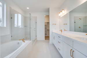 Full bath featuring a shower stall, double vanity, a bath, a walk in closet, and recessed lighting