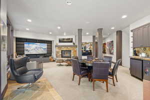 Dining room featuring a fireplace, light colored carpet, and recessed lighting