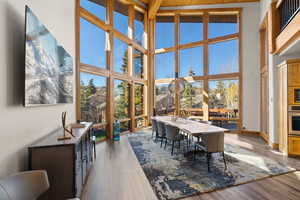Office area with light wood-type flooring, a towering ceiling, wooden ceiling, and a wall of windows