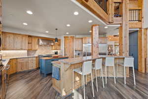Kitchen featuring light brown cabinetry, a kitchen bar, butcher block countertops, recessed lighting, and appliances with stainless steel finishes