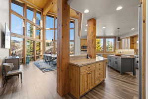Kitchen with dark wood finished floors, a center island, light stone counters, decorative light fixtures, and recessed lighting