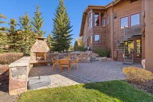 View of patio with stairs and an outdoor stone fireplace