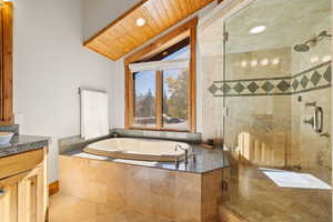 Full bath featuring vanity, a shower stall, lofted ceiling, a garden tub, and wood ceiling