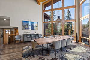 Dining area with dark wood finished floors, a high ceiling, and beam ceiling