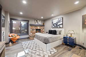 Bedroom featuring wood finished floors, recessed lighting, and a fireplace