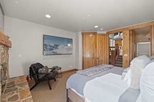 Bedroom featuring carpet, a stone fireplace, and recessed lighting