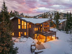 Snow covered back of property with a wooden deck