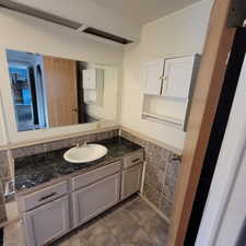Bathroom featuring vanity, a wainscoted wall, and tile walls