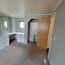 Unfurnished office featuring a textured ceiling, light carpet, and built in desk