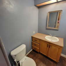Half bathroom featuring vanity and dark wood-type flooring