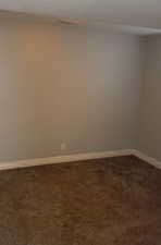 Spare room with dark colored carpet and baseboards