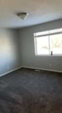 Unfurnished room featuring dark colored carpet