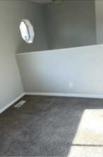 Empty room featuring dark carpet and baseboards