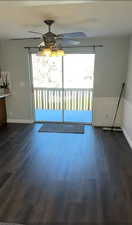Unfurnished dining area featuring plenty of natural light, a ceiling fan, and dark wood-style flooring