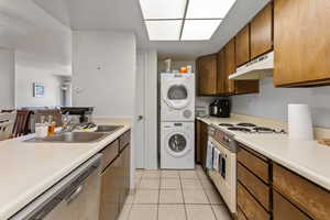 Kitchen with white electric stove, dishwasher, light countertops, and under cabinet range hood