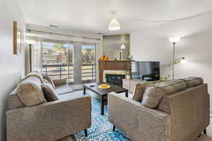 Living area featuring a glass covered fireplace and a textured ceiling