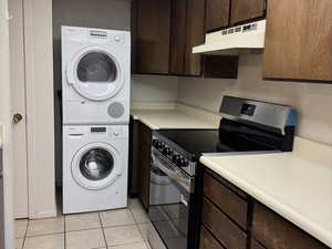 Kitchen with dark brown cabinetry, electric range, light countertops, and estacked washer and dryer