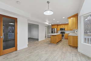 Kitchen with a kitchen island, light countertops, a breakfast bar, stainless steel appliances, and light wood-type flooring