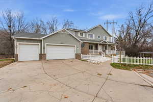 View of front of property featuring a porch, concrete driveway, a fenced front yard, an attached garage, and stucco siding