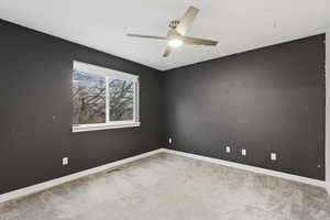 Carpeted spare room with baseboards and ceiling fan