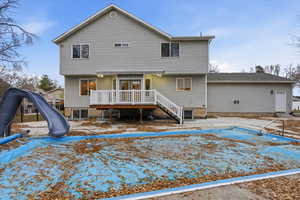 Rear view of house with a covered pool, a wooden deck, and stairs