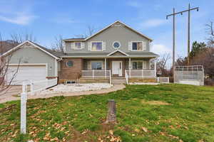 Traditional-style home featuring a porch, an attached garage, driveway, and an exterior structure