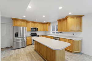 Kitchen with appliances with stainless steel finishes, light wood-type flooring, light countertops, and recessed lighting