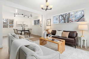 Living room featuring crown molding, wood finished floors, a chandelier, and rail lighting