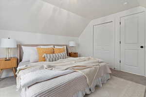 Carpeted bedroom featuring vaulted ceiling and a closet