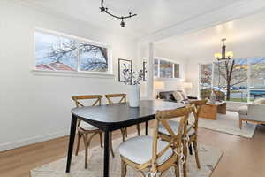 Dining room featuring light wood-type flooring, a chandelier, plenty of natural light, and ornamental molding