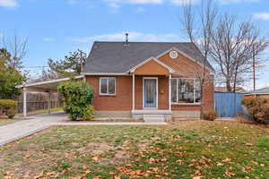 View of front of house with an attached carport, brick siding, driveway, and roof with shingles