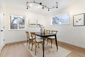Dining space with healthy amount of natural light, light wood-style floors, rail lighting, and crown molding