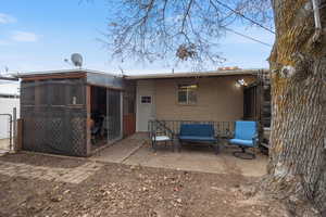 Rear view of house with brick siding, a patio area, a sunroom, and a gate