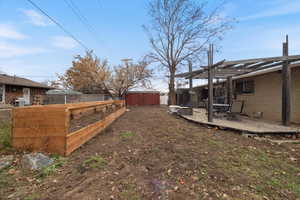 Fenced backyard with a wooden deck, a storage shed, and a pergola