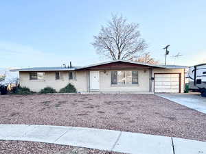 Single story home featuring a garage, brick siding, and driveway