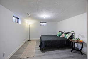 Bedroom with a textured ceiling and wood finished floors