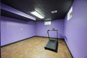 Exercise room with a textured ceiling and baseboards