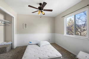 Unfurnished bedroom featuring a closet, a ceiling fan, and dark carpet