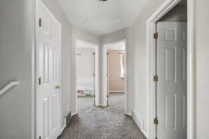 Hall with attic access and dark colored carpet