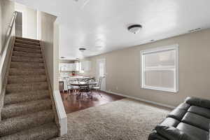 Living room with stairs, a textured ceiling, and dark wood-style flooring