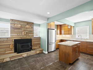 Kitchen featuring freestanding refrigerator, plenty of natural light, light stone counters, a center island, and recessed lighting