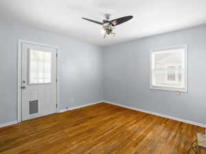 Empty room featuring wood-type flooring, plenty of natural light, and ceiling fan