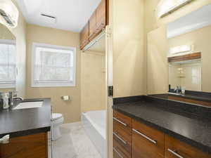 Bathroom featuring vanity, light marble finish flooring, and a tub to relax in