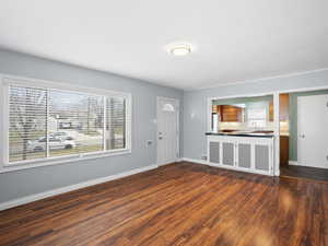 Unfurnished living room with dark wood finished floors and baseboards