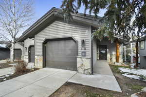 View of front of property featuring stone siding, driveway, and an attached garage