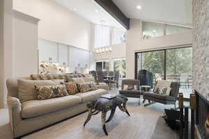 Living room featuring high vaulted ceiling, a chandelier, and a stone fireplace