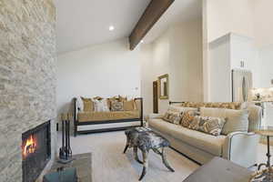 Living room featuring high vaulted ceiling, a fireplace, light wood finished floors, beamed ceiling, and recessed lighting