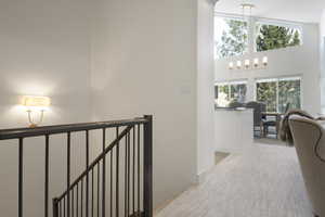 Hall with a chandelier, high vaulted ceiling, and an upstairs landing