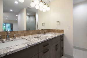 Bathroom featuring double vanity, a stall shower, recessed lighting, light tile patterned flooring, and decorative backsplash
